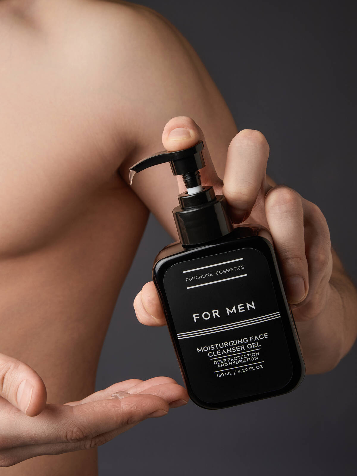 Флакон FOR MEN в руке на фоне обнажённого торса, низкий ключ света